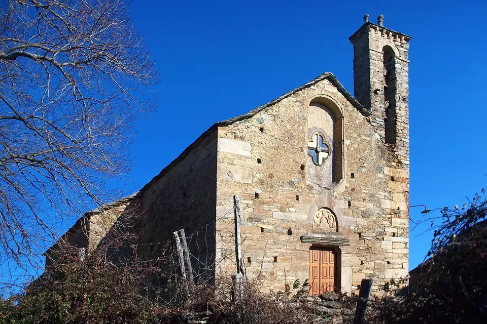 Église romane en pierre à clocher carré, sur une hauteur boisée de Castagniccia, sous un ciel bleu