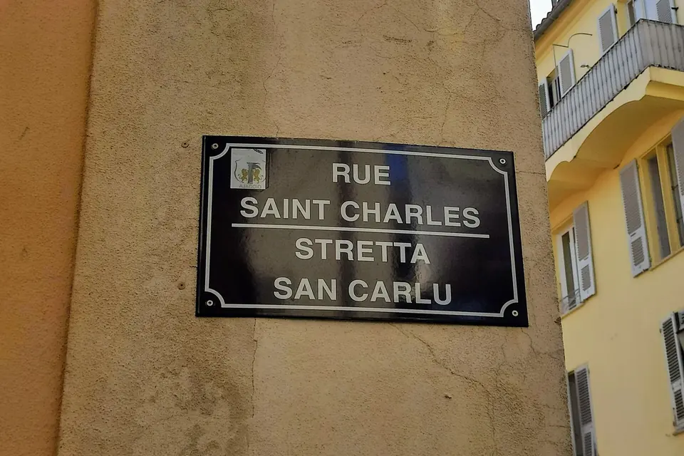 Plaque de rue bilingue sur un mur d'Ajaccio : « Rue Saint-Charles » en français et « Stretta San Carlu » en corse